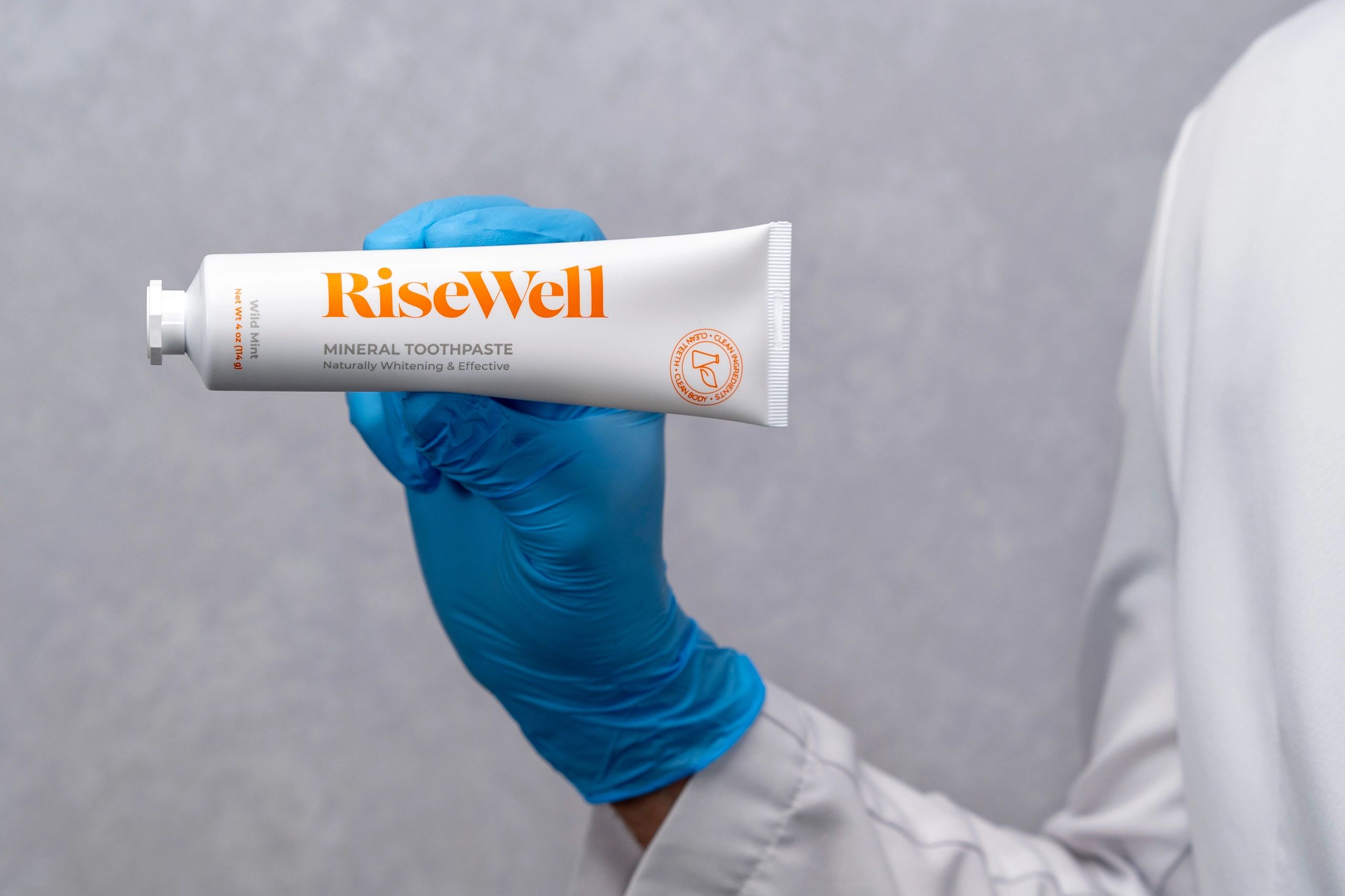 A gloved hand holds a tube of toothpaste.