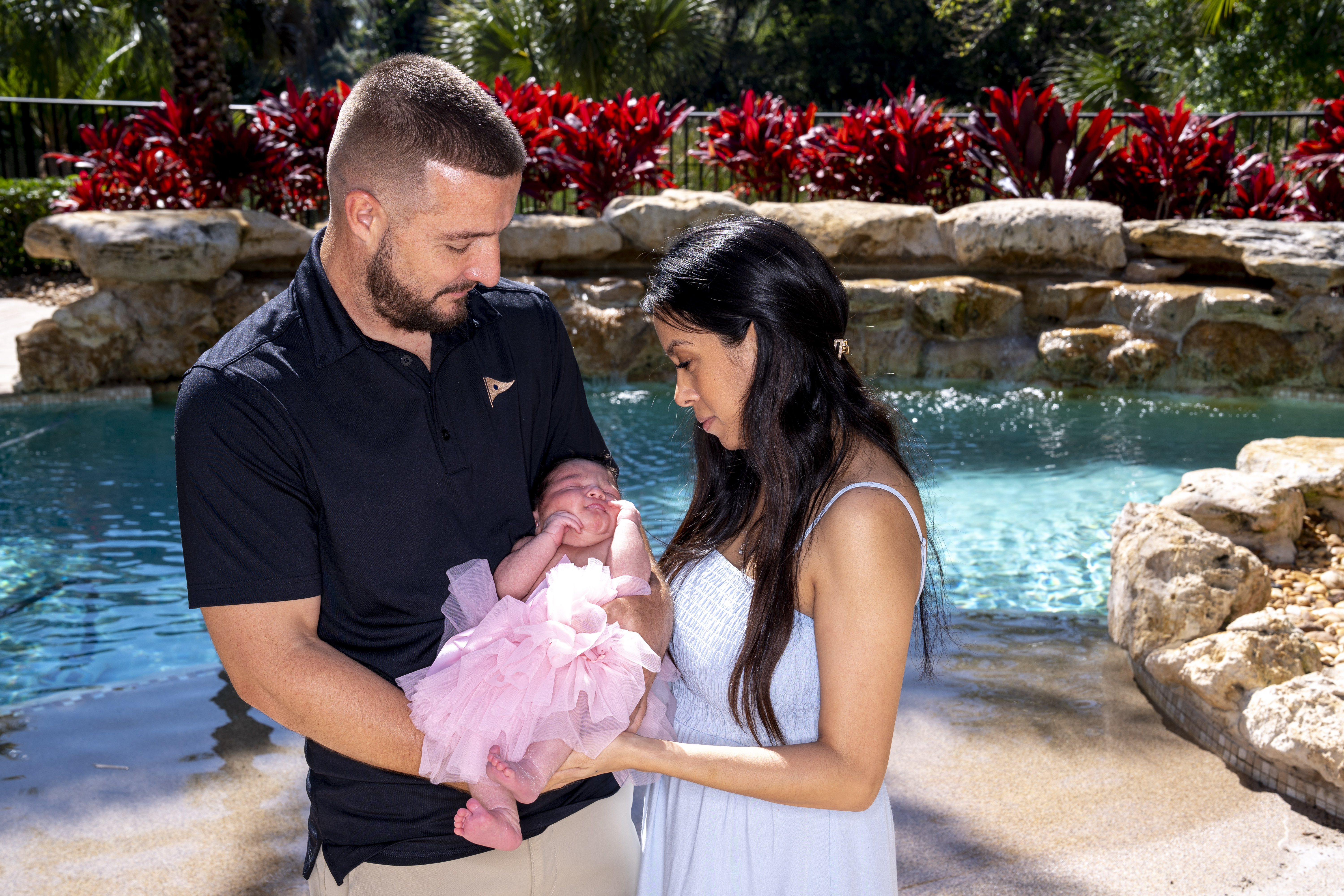 A man and woman holding a baby girl by a pool.